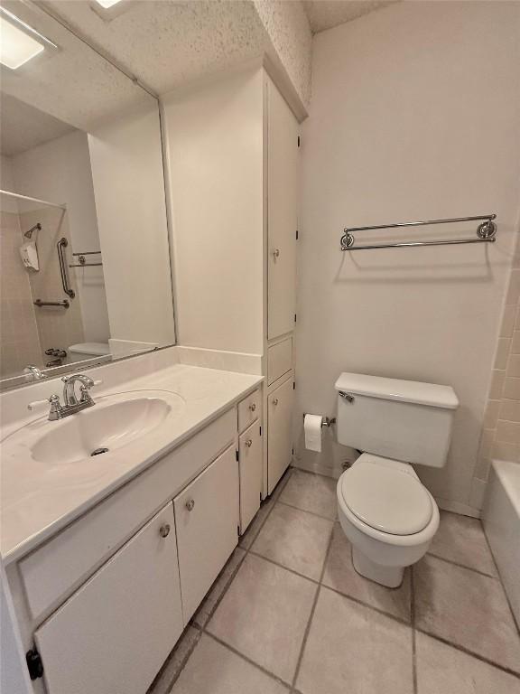 bathroom with tile patterned flooring, a textured ceiling, toilet, and vanity