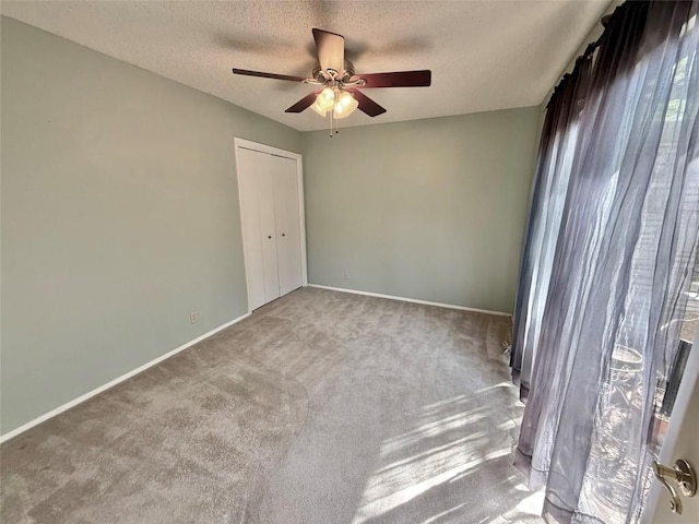 carpeted empty room featuring baseboards, a ceiling fan, and a textured ceiling