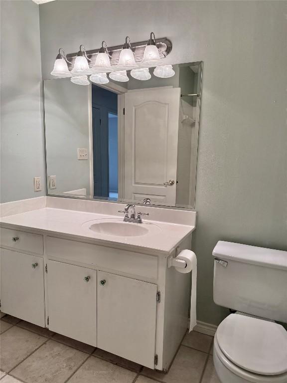 bathroom with toilet, vanity, and tile patterned floors