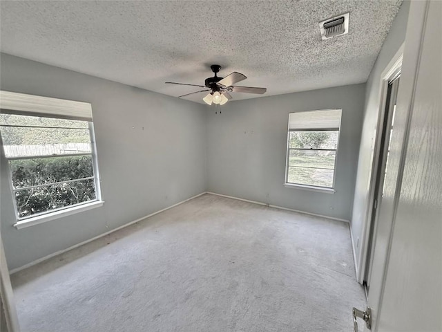 carpeted spare room featuring baseboards, a ceiling fan, visible vents, and a textured ceiling