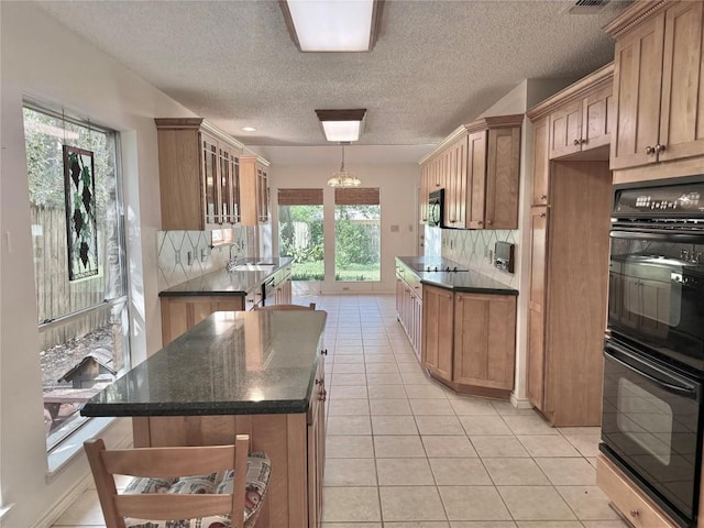 kitchen with a sink, backsplash, black appliances, and light tile patterned flooring