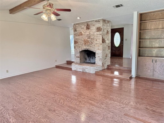 unfurnished living room with a textured ceiling, visible vents, a ceiling fan, wood finished floors, and a fireplace