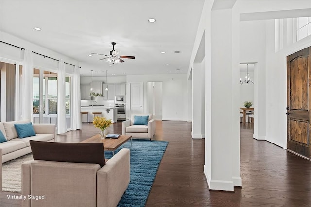 living room with ceiling fan with notable chandelier, dark hardwood / wood-style floors, and sink