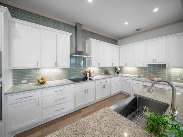 kitchen featuring tasteful backsplash, white cabinetry, sink, and wall chimney exhaust hood