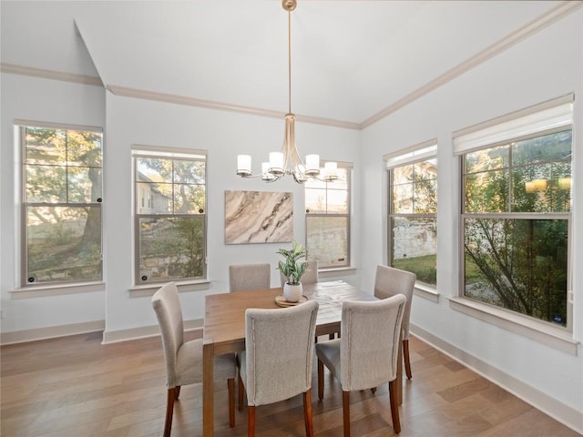 dining area featuring hardwood / wood-style flooring, a healthy amount of sunlight, ornamental molding, and an inviting chandelier