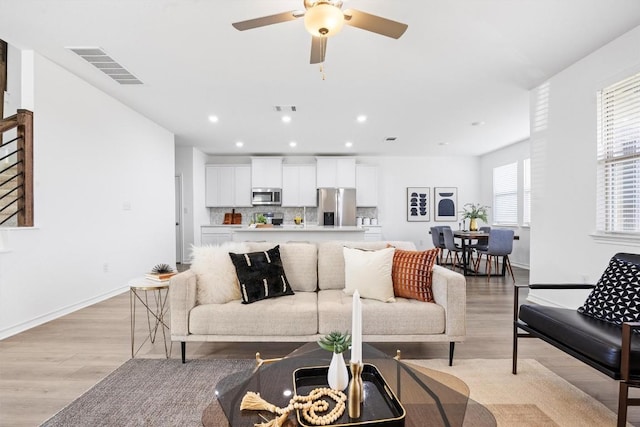 living room with light hardwood / wood-style flooring, ceiling fan, and a healthy amount of sunlight