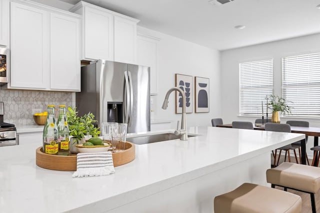 kitchen featuring decorative backsplash, sink, white cabinetry, and stainless steel appliances