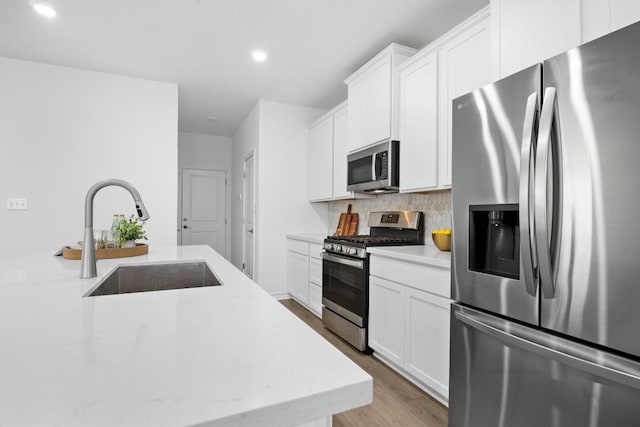 kitchen featuring decorative backsplash, sink, white cabinets, and stainless steel appliances