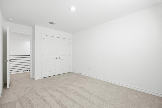 unfurnished bedroom with light carpet and a closet