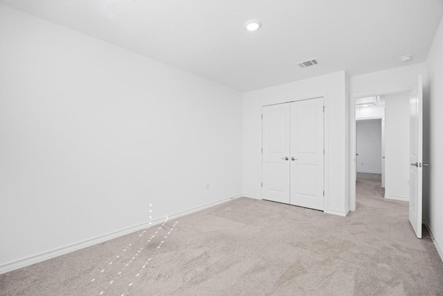 unfurnished bedroom with light carpet and a closet