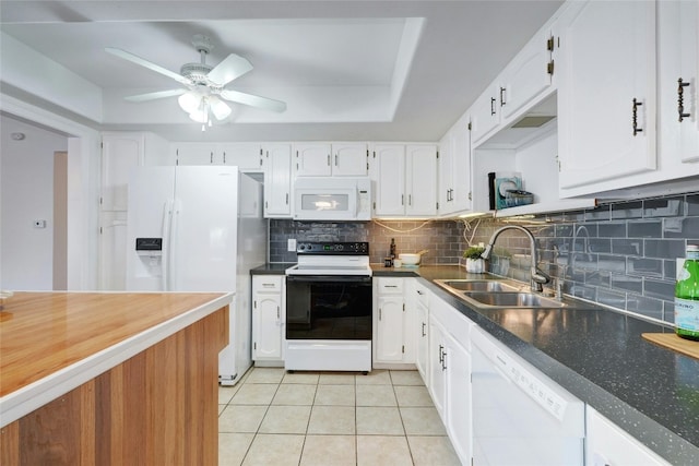 kitchen with white cabinetry, sink, white appliances, a tray ceiling, and light tile patterned floors