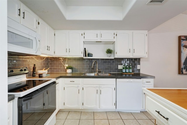 kitchen featuring white appliances, sink, light tile patterned floors, a tray ceiling, and white cabinetry