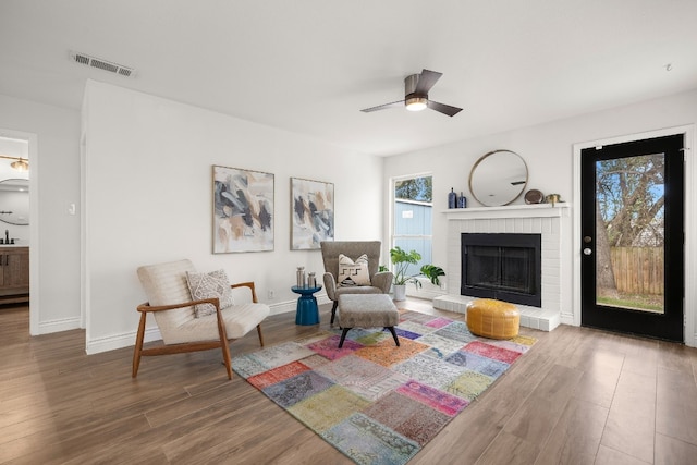 sitting room featuring ceiling fan, a fireplace, wood-type flooring, and sink