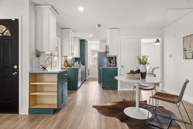 kitchen featuring stainless steel refrigerator, sink, blue cabinets, wood-type flooring, and white cabinets