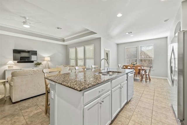 kitchen featuring sink, dark stone countertops, a center island with sink, white cabinets, and appliances with stainless steel finishes