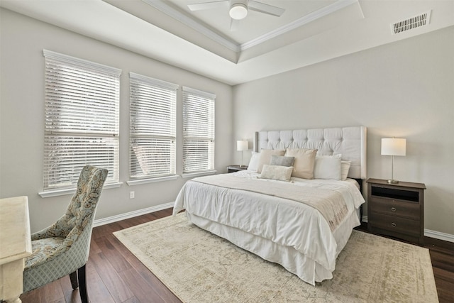 bedroom featuring ceiling fan, dark hardwood / wood-style flooring, a raised ceiling, and crown molding