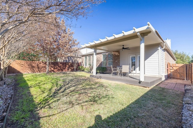 back of house featuring a lawn, ceiling fan, and a patio area