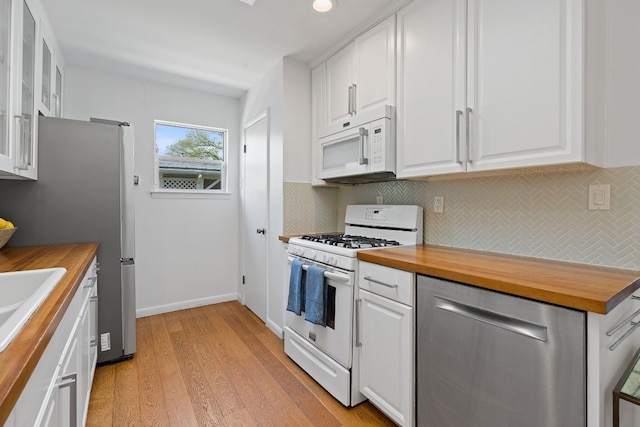 kitchen with light hardwood / wood-style flooring, white cabinets, wooden counters, and appliances with stainless steel finishes