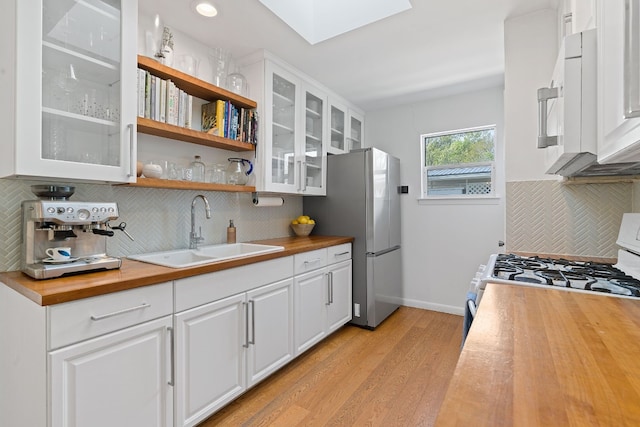 kitchen with wood counters, white appliances, sink, light hardwood / wood-style flooring, and white cabinets