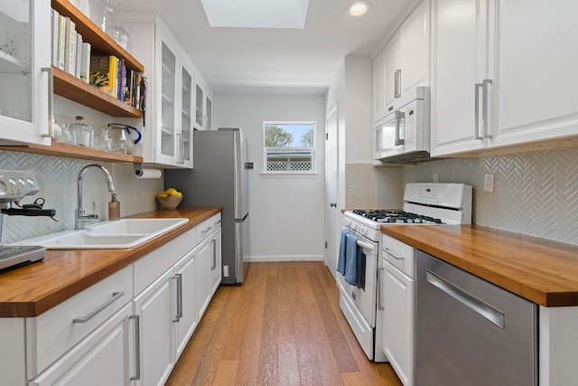 kitchen featuring white cabinets, butcher block countertops, stove, and sink