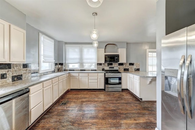 kitchen featuring light stone countertops, appliances with stainless steel finishes, decorative backsplash, and pendant lighting