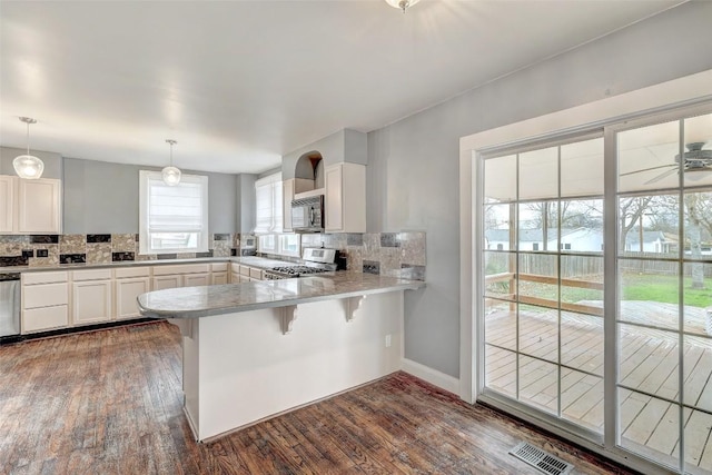 kitchen with backsplash, kitchen peninsula, decorative light fixtures, white cabinets, and range