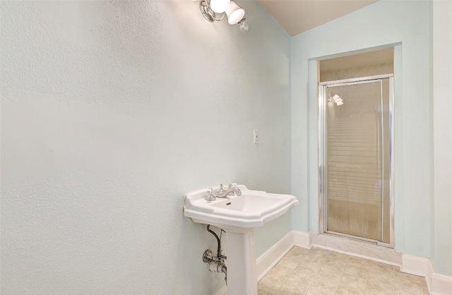 bathroom featuring a shower with door and sink