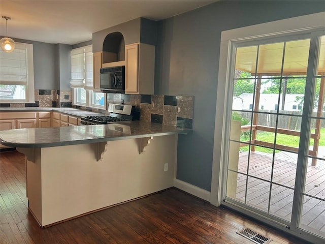 1710 Lexington St, Taylor, TX 76574 - kitchen featuring stainless steel gas stove, black microwave, plenty of natural light, and backsplash