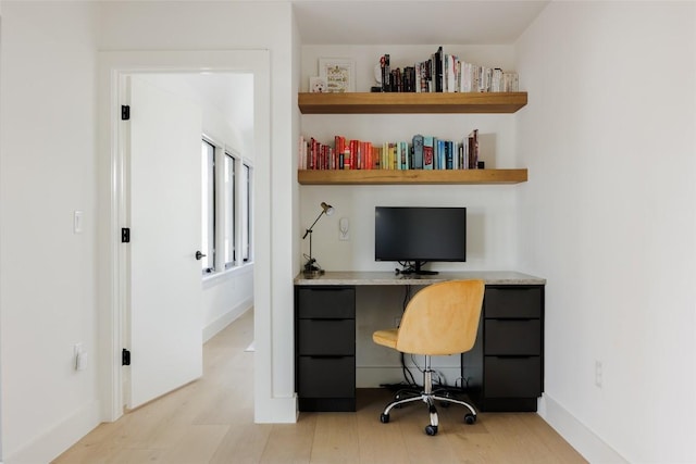 home office with light hardwood / wood-style floors and built in desk