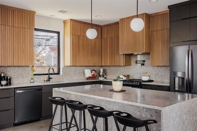 kitchen with sink, hanging light fixtures, stainless steel appliances, a kitchen breakfast bar, and a kitchen island