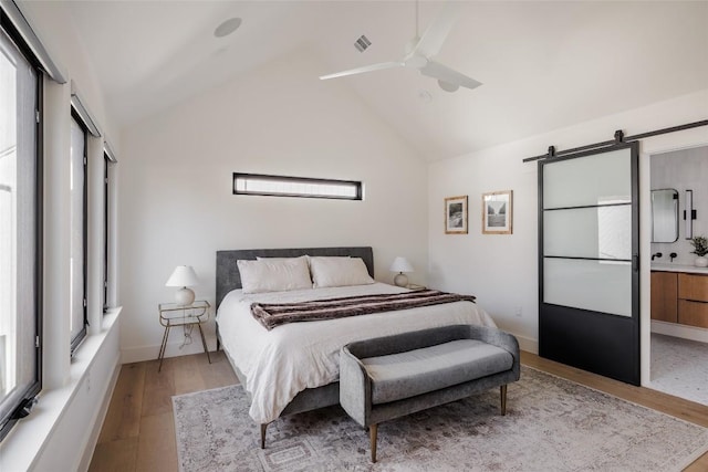 bedroom featuring ceiling fan, ensuite bath, light wood-type flooring, and multiple windows