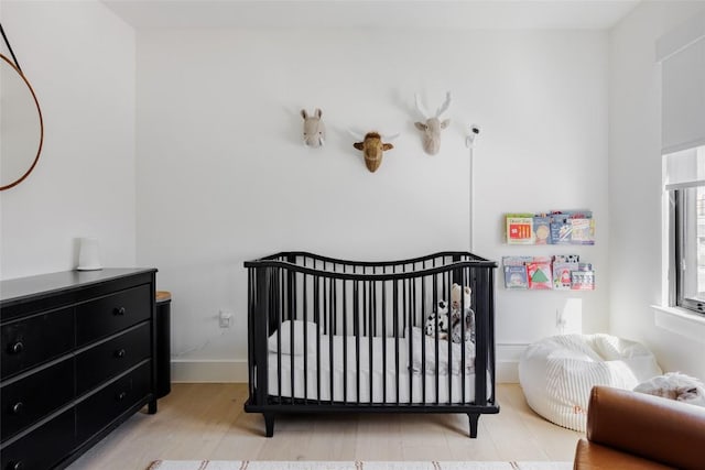 bedroom featuring light hardwood / wood-style flooring and a nursery area