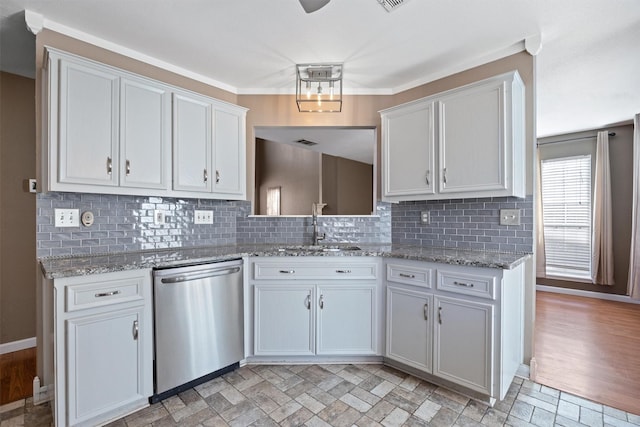 kitchen with light stone counters, stainless steel dishwasher, decorative backsplash, white cabinets, and sink