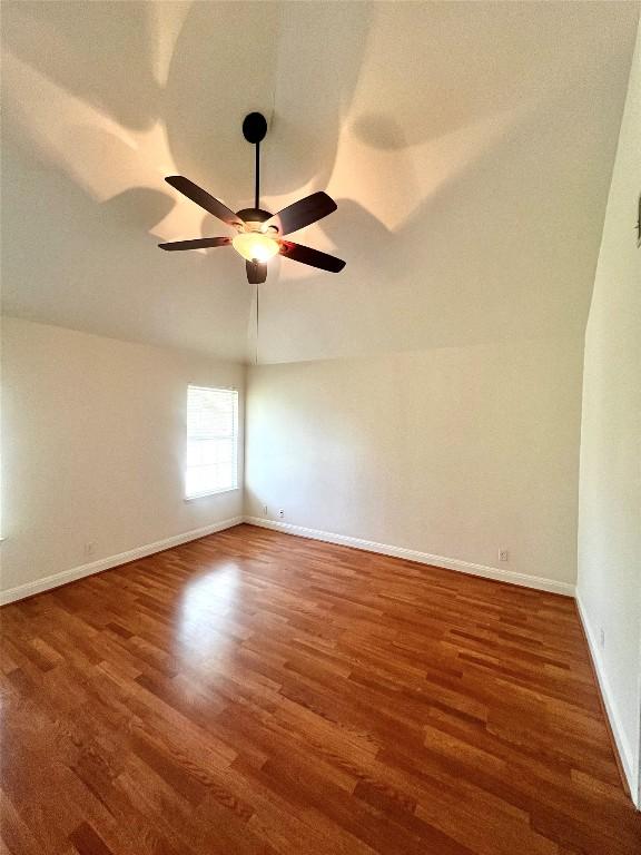 spare room featuring baseboards, ceiling fan, and wood finished floors