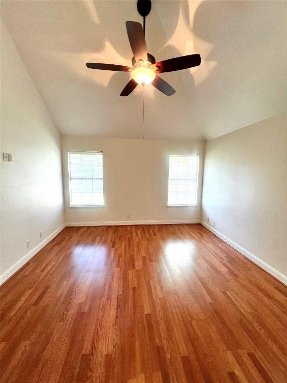 unfurnished room with a ceiling fan, baseboards, wood finished floors, and lofted ceiling