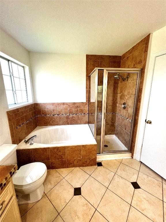full bathroom with tile patterned floors, a shower stall, toilet, and a garden tub