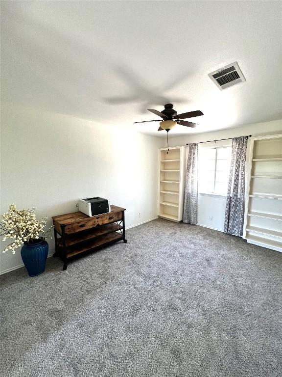 interior space with visible vents, carpet floors, and ceiling fan