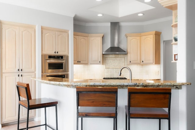 kitchen with crown molding, wall chimney range hood, light stone countertops, and tasteful backsplash