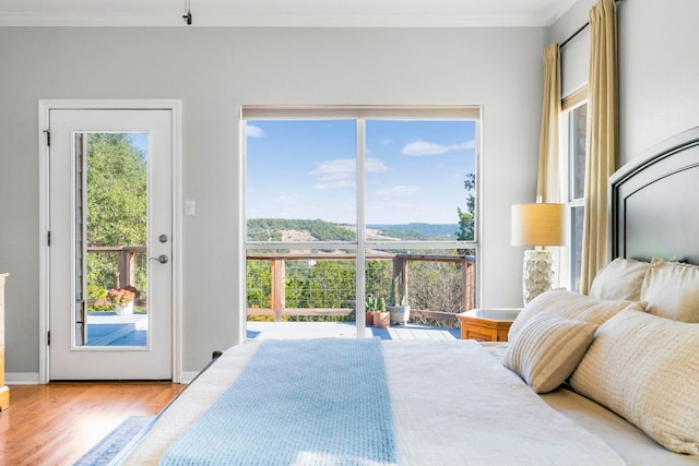 bedroom featuring access to exterior, ornamental molding, and light wood-type flooring