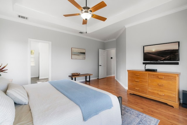 bedroom with ceiling fan, light hardwood / wood-style flooring, ornamental molding, and a raised ceiling