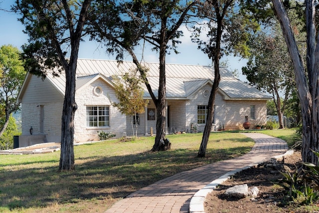 view of front of home featuring metal roof, a front lawn, a standing seam roof, and stone siding