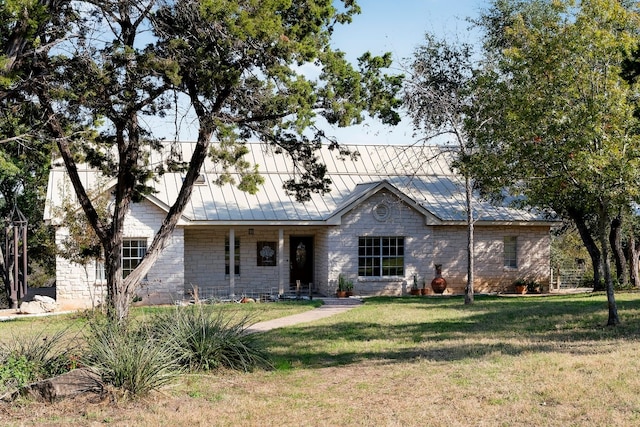 view of front facade with metal roof, stone siding, a standing seam roof, and a front yard