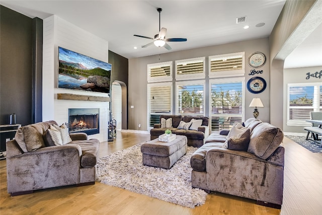 living room with ceiling fan, light wood-type flooring, and a fireplace