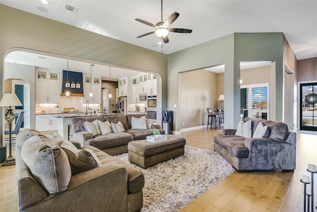 living room with sink, light hardwood / wood-style floors, and ceiling fan