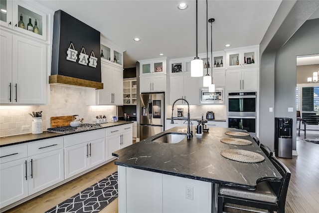 kitchen with appliances with stainless steel finishes, sink, an island with sink, and white cabinets