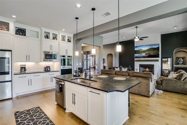 kitchen featuring stainless steel appliances, sink, an island with sink, and white cabinets