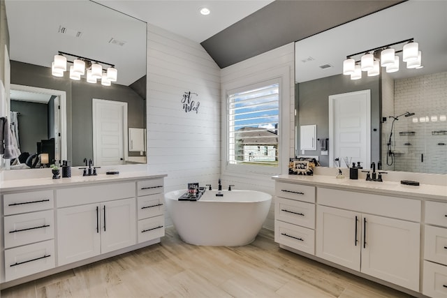 bathroom with lofted ceiling, vanity, and plus walk in shower