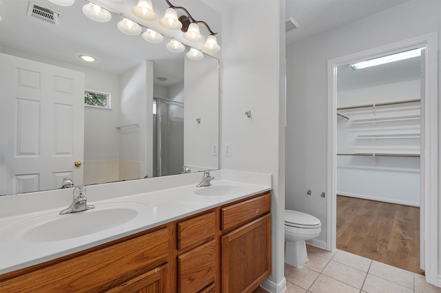 bathroom with an enclosed shower, vanity, toilet, and tile patterned flooring