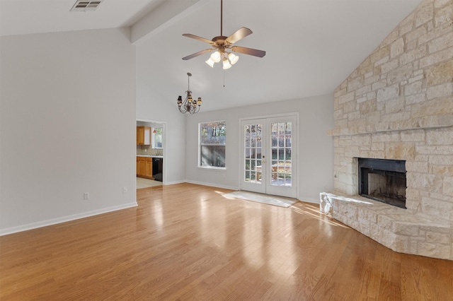 unfurnished living room featuring a fireplace, beamed ceiling, light hardwood / wood-style flooring, high vaulted ceiling, and french doors