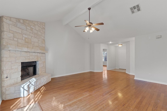 unfurnished living room featuring ceiling fan, hardwood / wood-style flooring, lofted ceiling with beams, and a fireplace